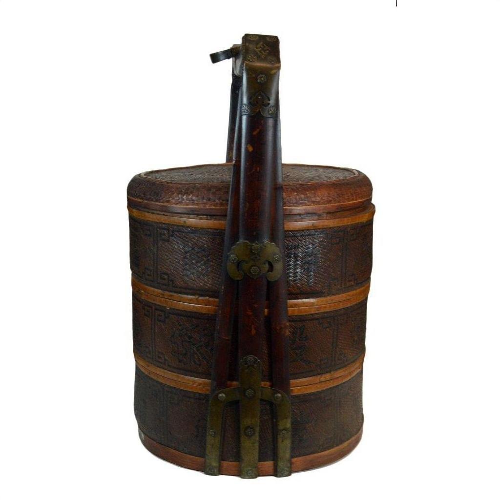 Brown wicker basket with lid, ornate carvings, tall handle, and metal accents on a white background.