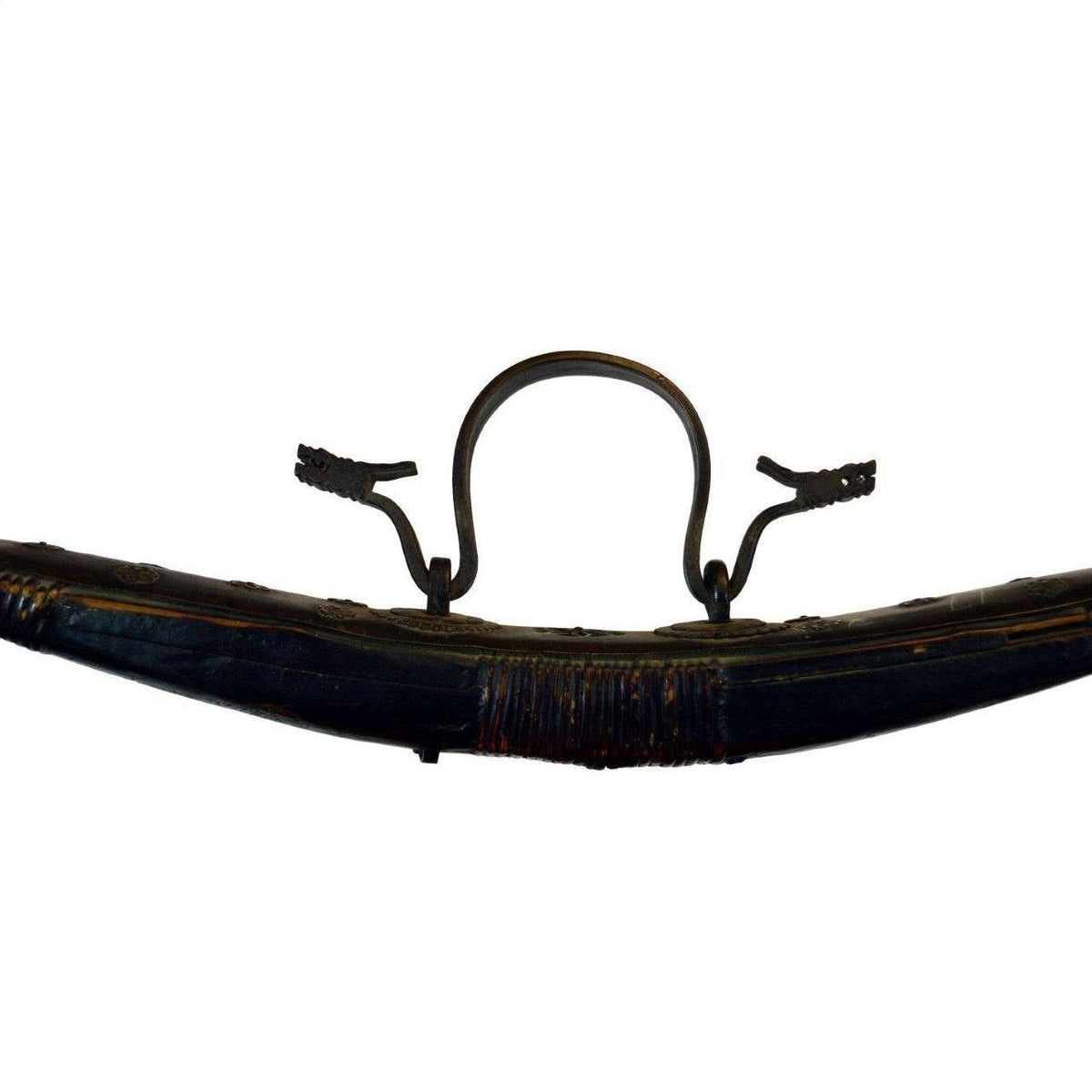 Close-up of a brown leather vintage saddle stirrup and strap next to a large wicker basket with lid on white background.