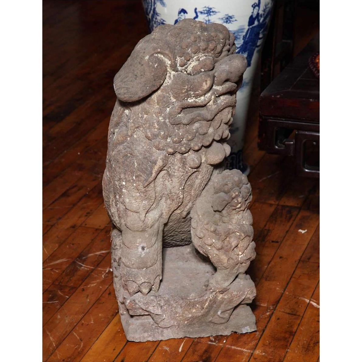 Stone lion sculpture with paw on a ball, gray tone, Ming Dynasty era, displayed on wooden floor.