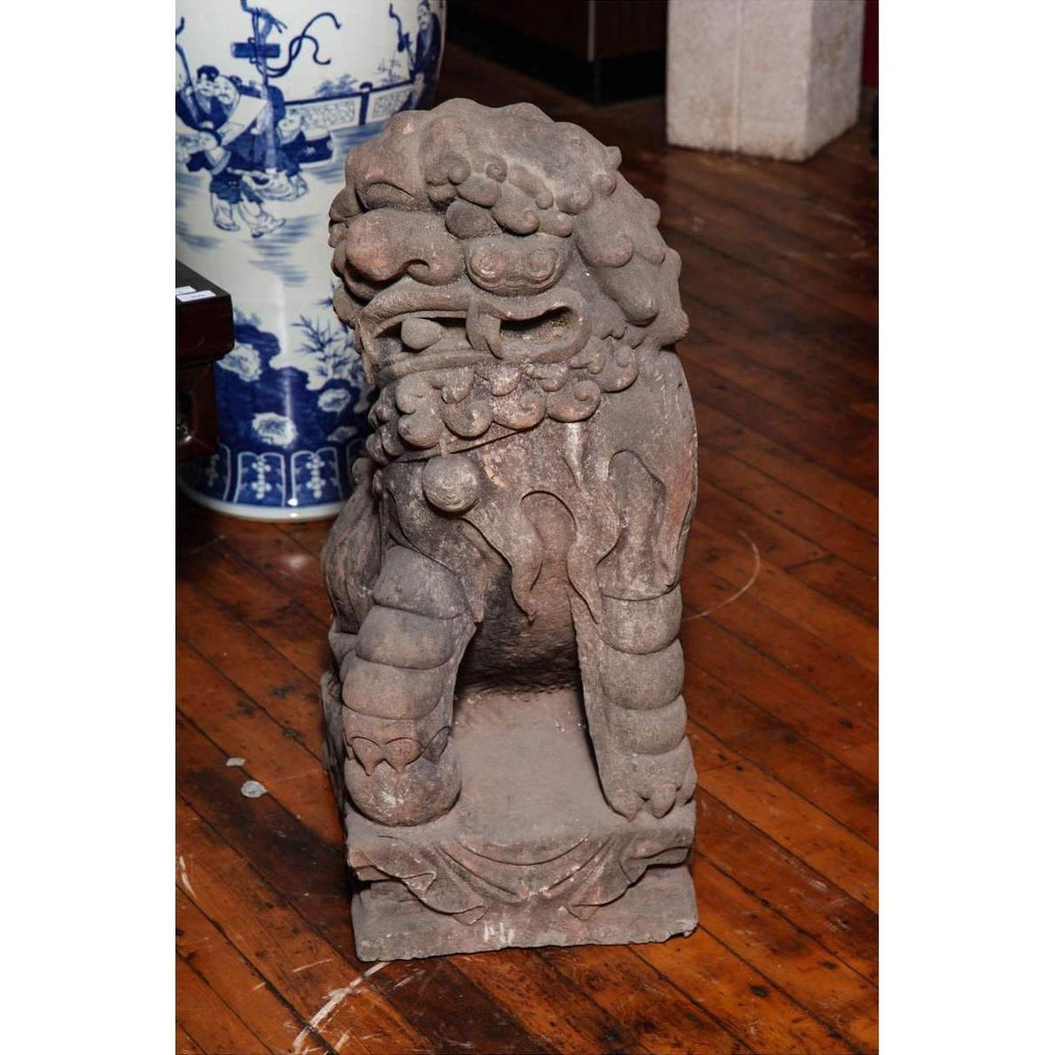Gray stone lion sculpture, Late Ming Dynasty China, on wooden floor beside blue and white vase indoors.