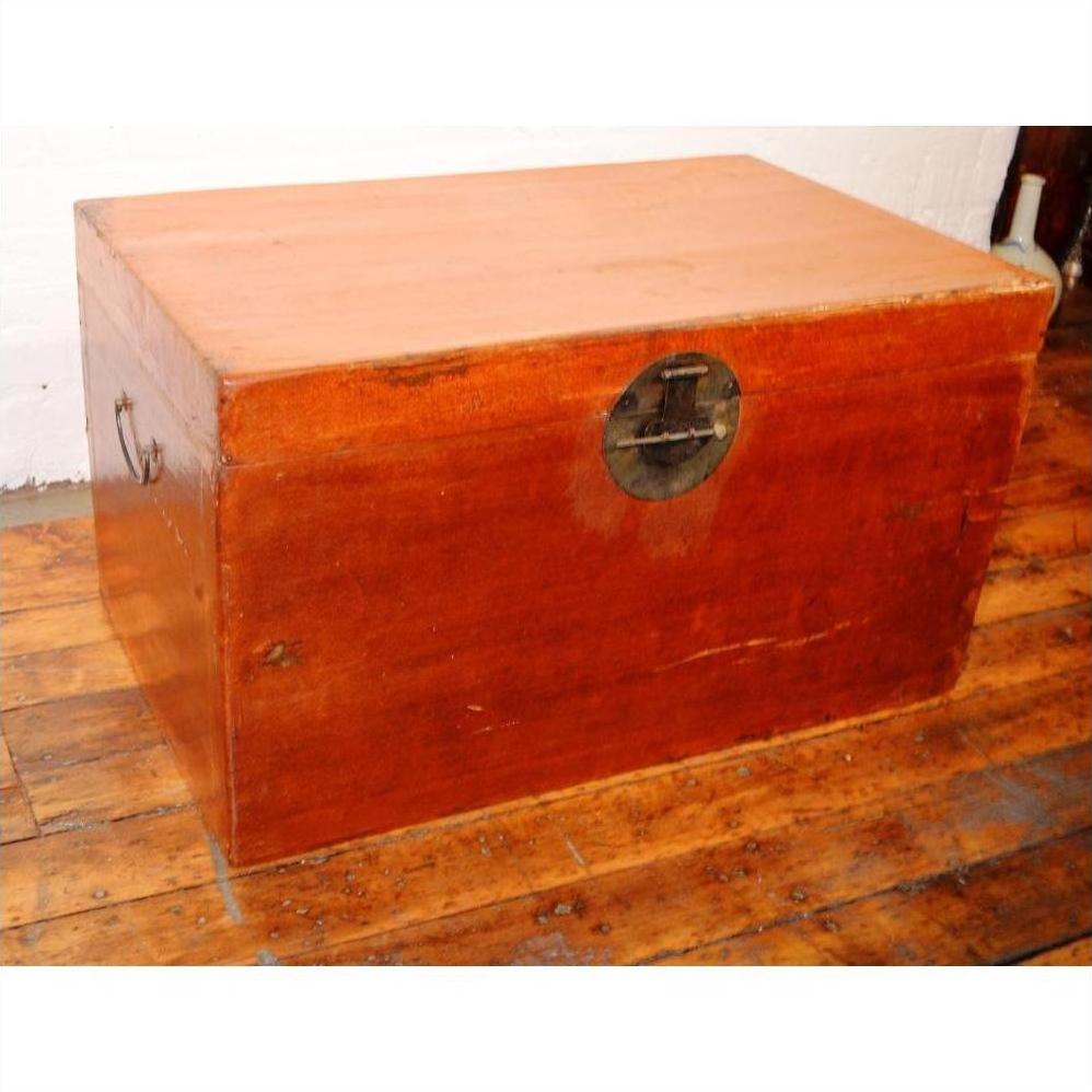 Brown leather coffee table trunk with metal lock on polished wooden floor against a white wall.