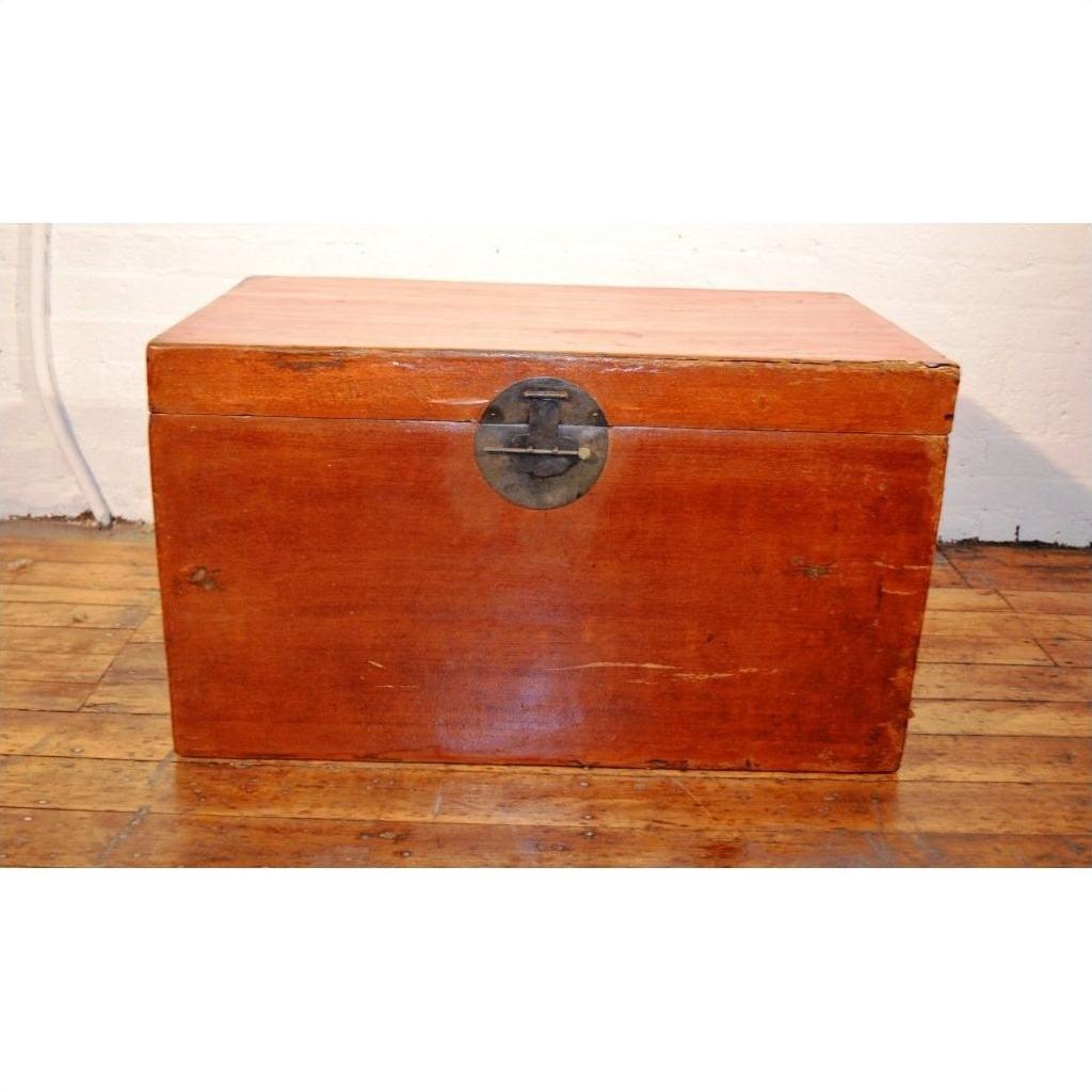 Brown leather coffee table trunk with dark metal latch on wooden floor, white wall background.