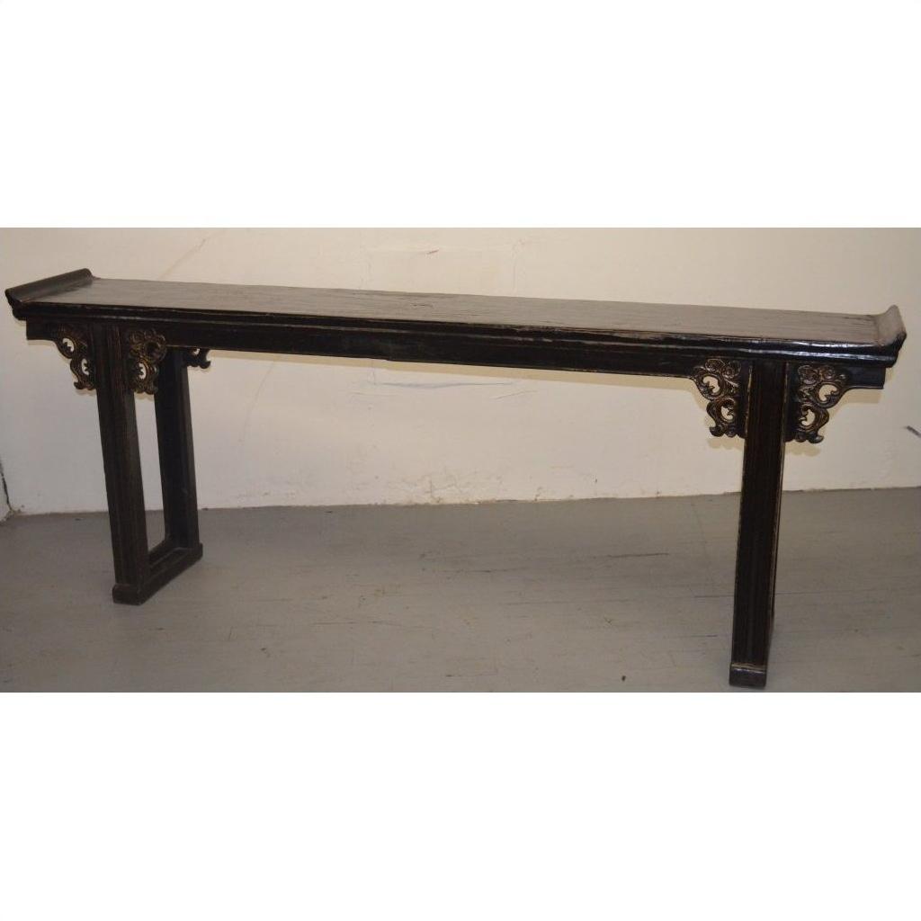 Brown wood Chinese altar table with carved spandrels and gold-accented side supports, set against a plain background.