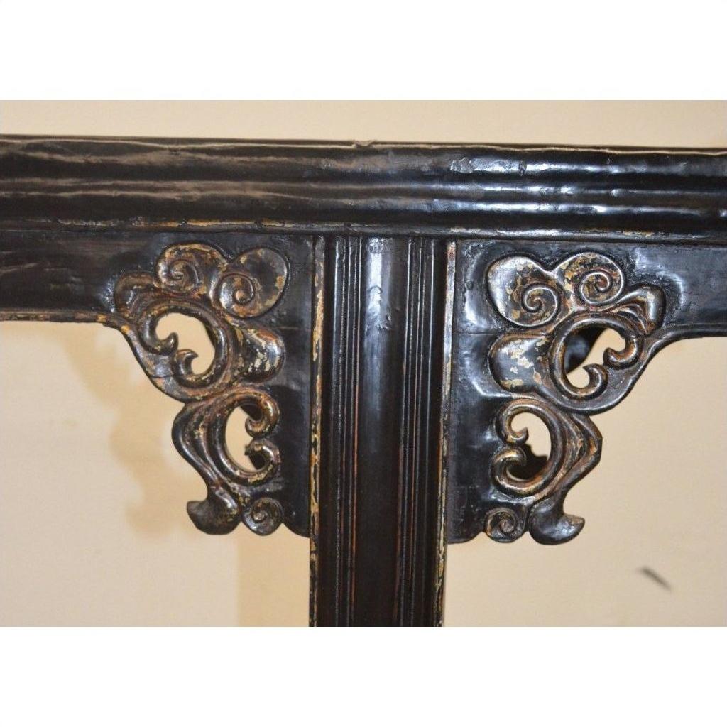 Close-up of dark wood antique Chinese altar table leg with intricate swirling carved spandrels.