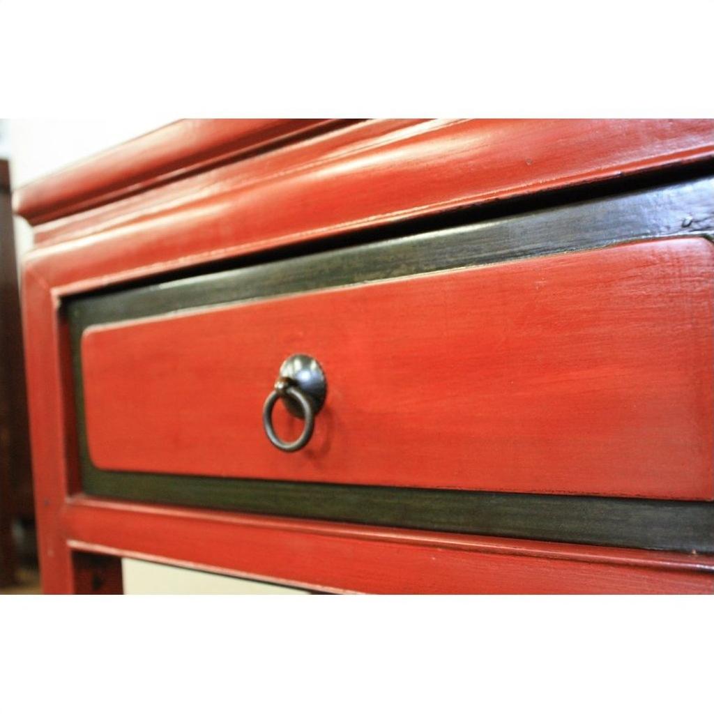 Close-up of red lacquer wood side table drawer with black trim and black metal ring pull handle.