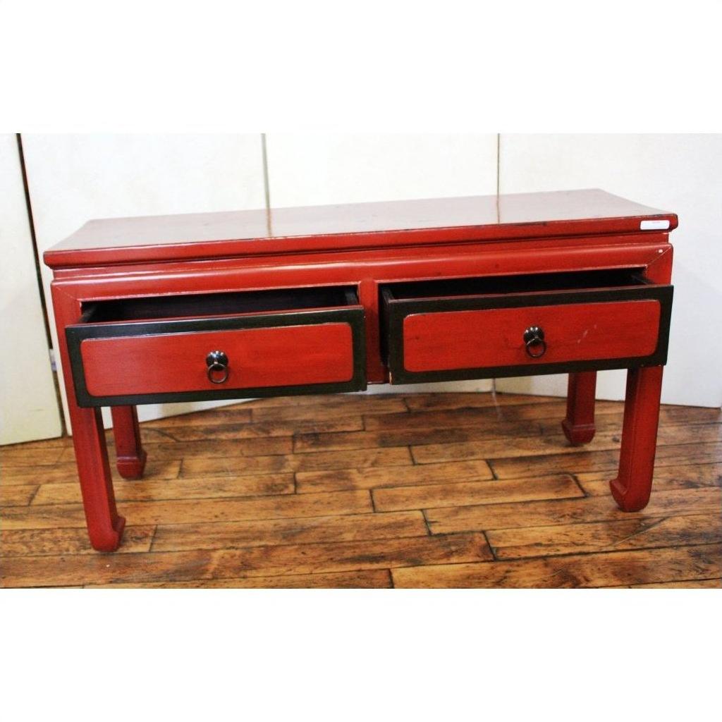 Red lacquer and black trim low side table with ring handles on a wooden floor.