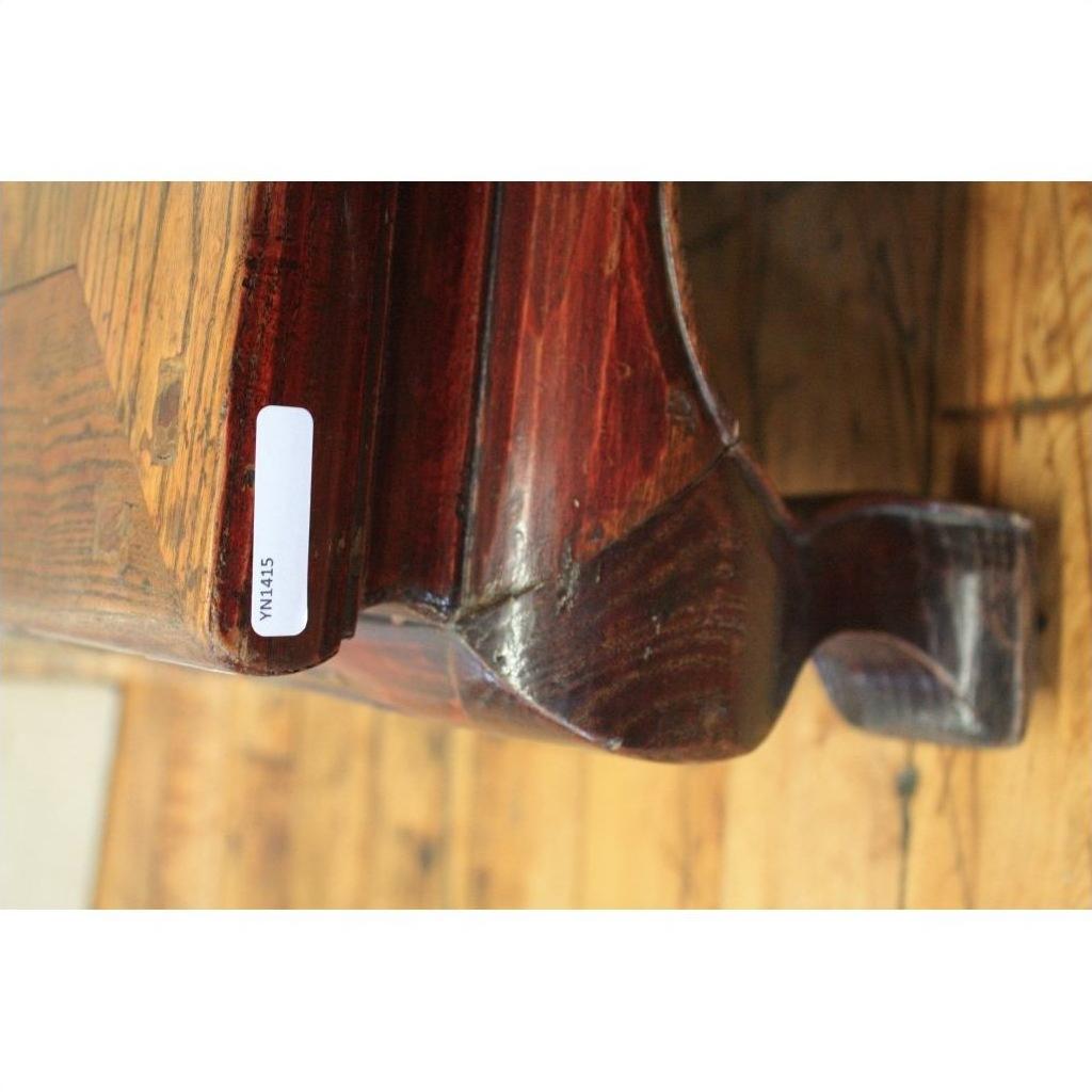Dark wood square table with curved edge on wooden floor, close-up view.