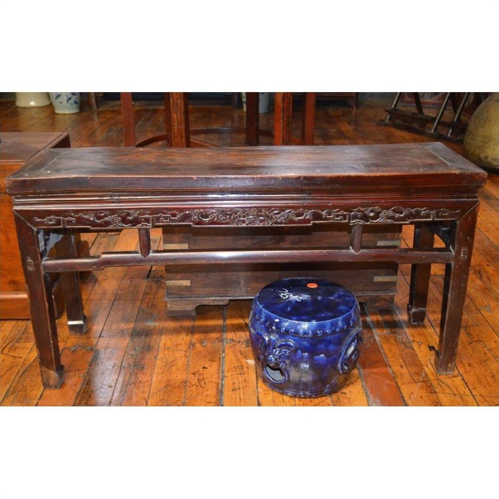 Brown carved wood low table beside a small blue ceramic stool on wooden flooring.