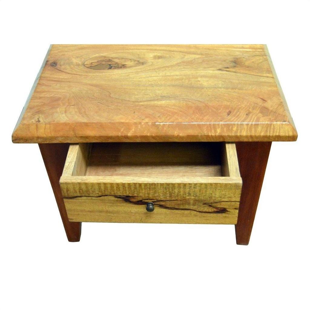 Brown mango wood side table with one front drawer and a partially open brass round pull, indoor setting.