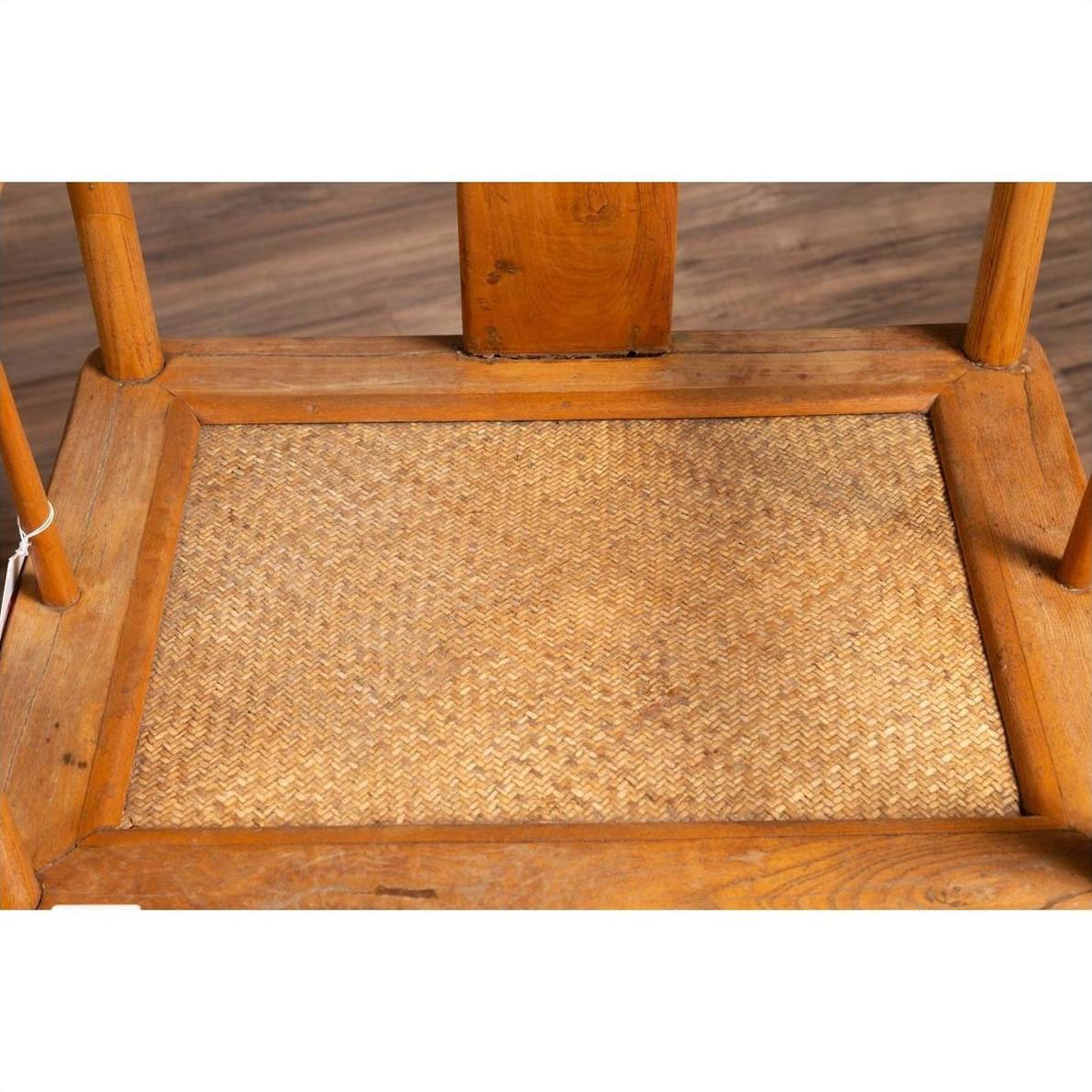Brown wood and rattan Ming Dynasty style wedding armchair close-up with curved arms, on wood flooring indoors.