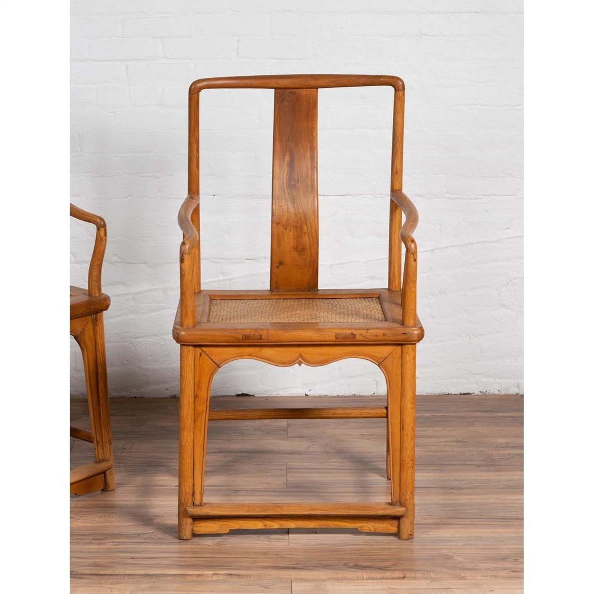 Brown wood and rattan armchairs with curved arms on wooden floor, Ming dynasty style, indoors.