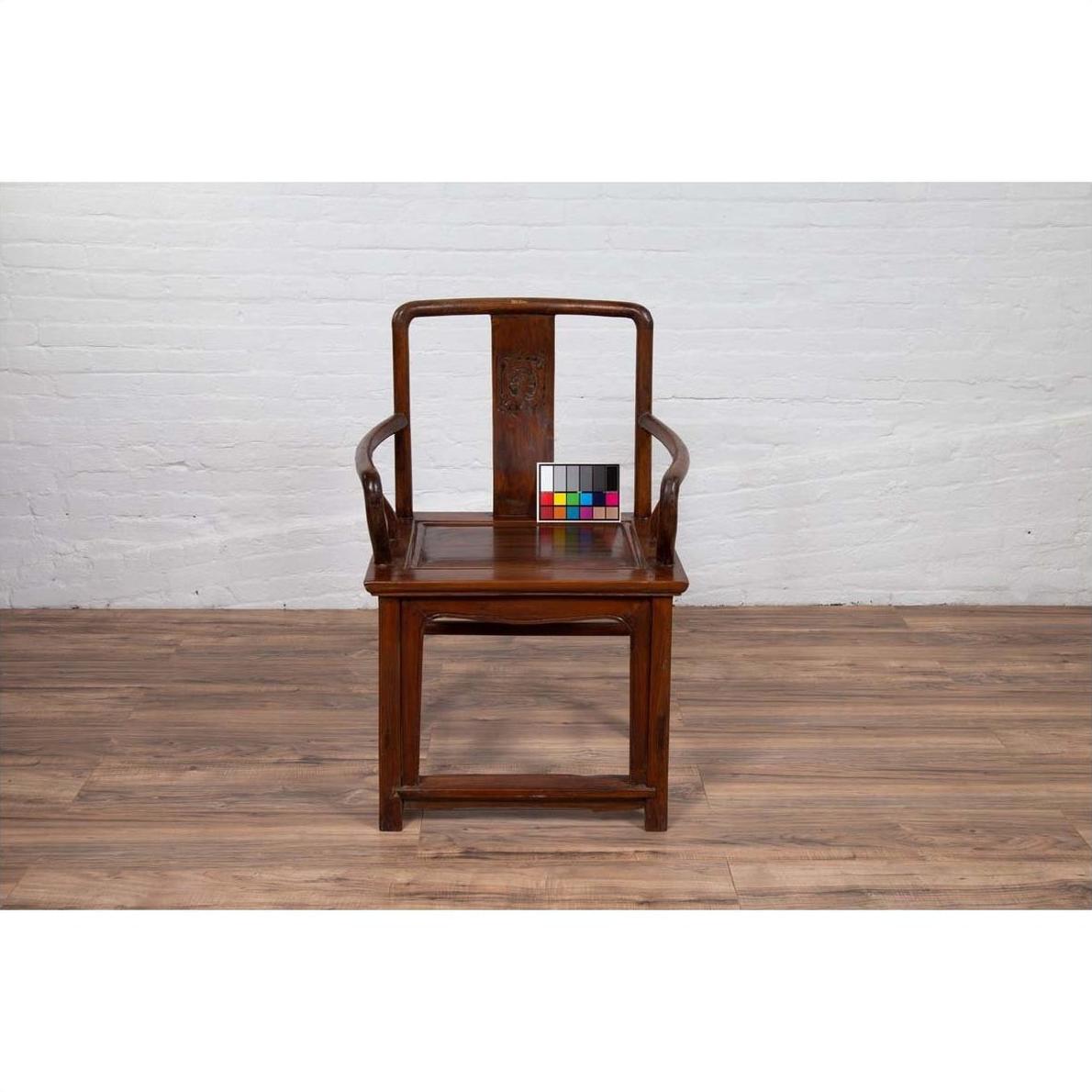 Brown wooden wedding chair with carved medallion and curving arms on wooden floor, color card on top.