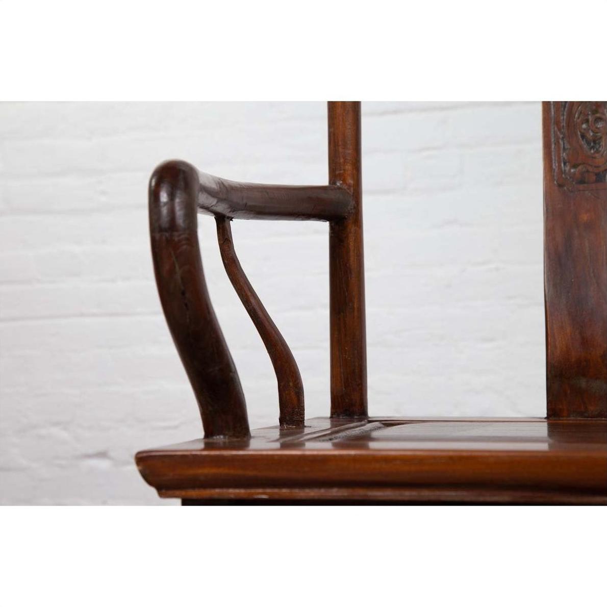 Close-up of brown wooden chair arms and seat with curved design, set indoors against a white brick wall.