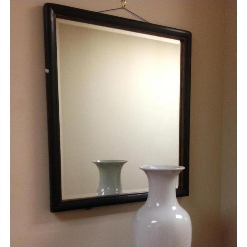Large white vase reflected in a mirror, with lighter wood-accented wall in the background.