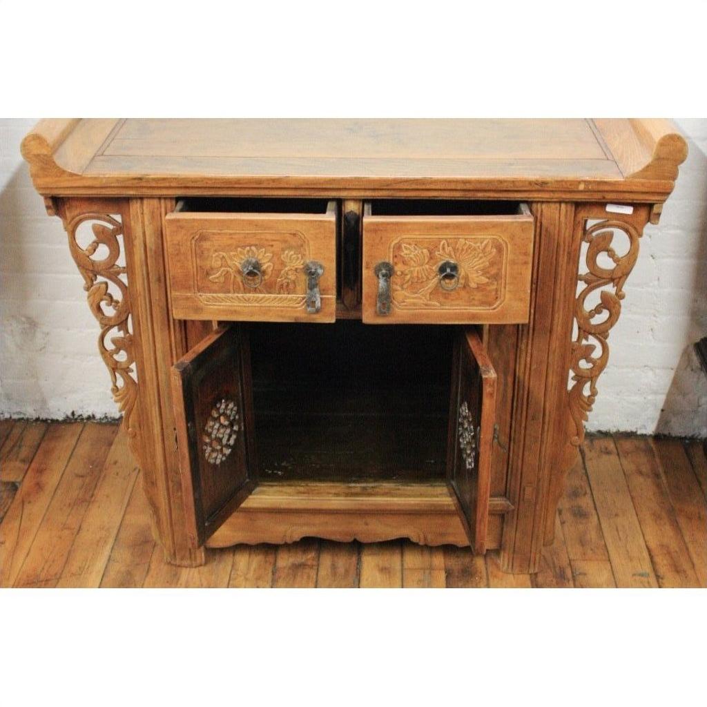 Natural elmwood altar cabinet with carved spandrels, two open drawers, and two lower doors on a wooden floor.