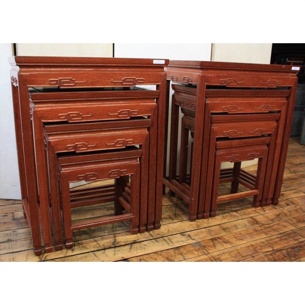 Brown wood nesting tables with carved geometric designs on a light-finished wooden floor.