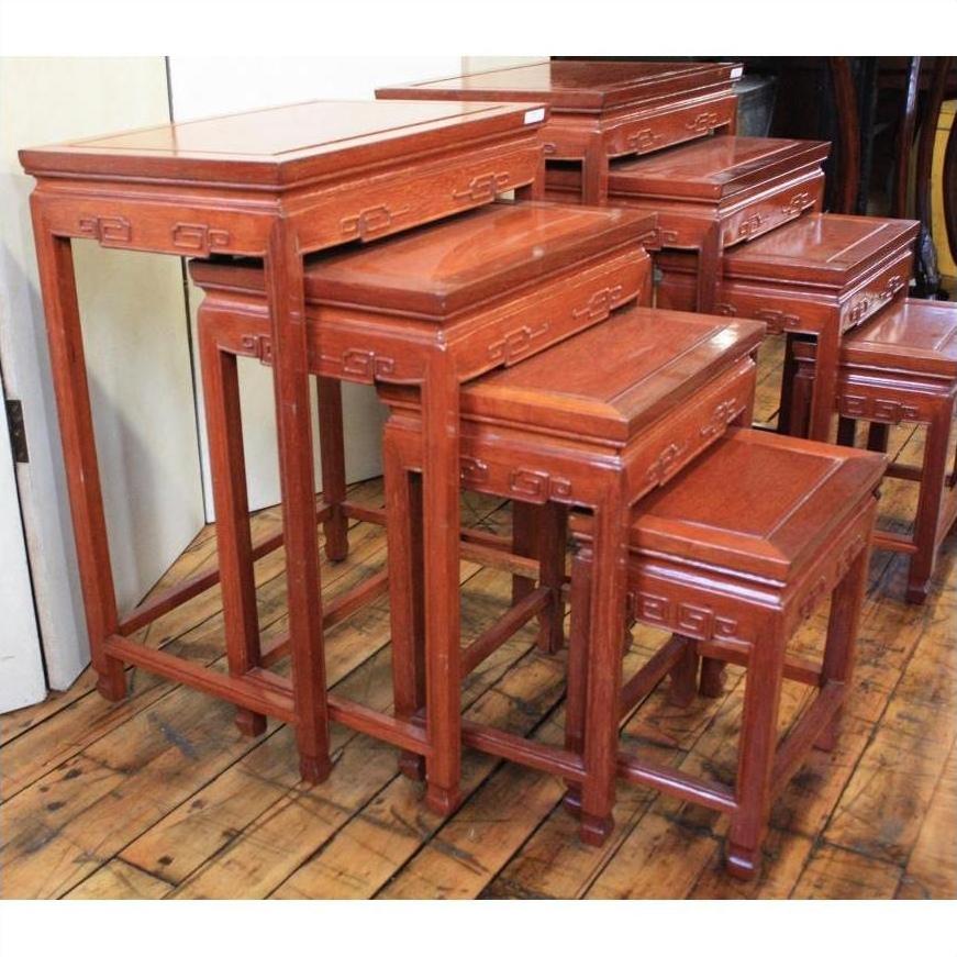 Wooden nesting tables with carved details, four sets arranged on a wooden floor, side-by-side display.