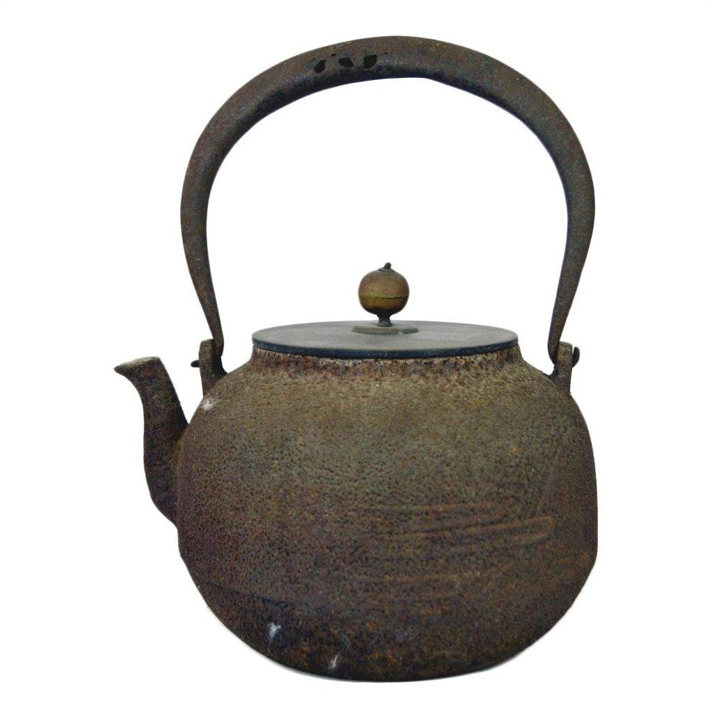 Close-up of rustic iron Japanese teapot with curved handle and round wooden lid knob, in good condition.
