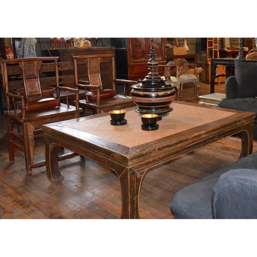 Black lacquer coffee table with two yellow cups and striped vase, surrounded by wooden chairs in a cozy room.