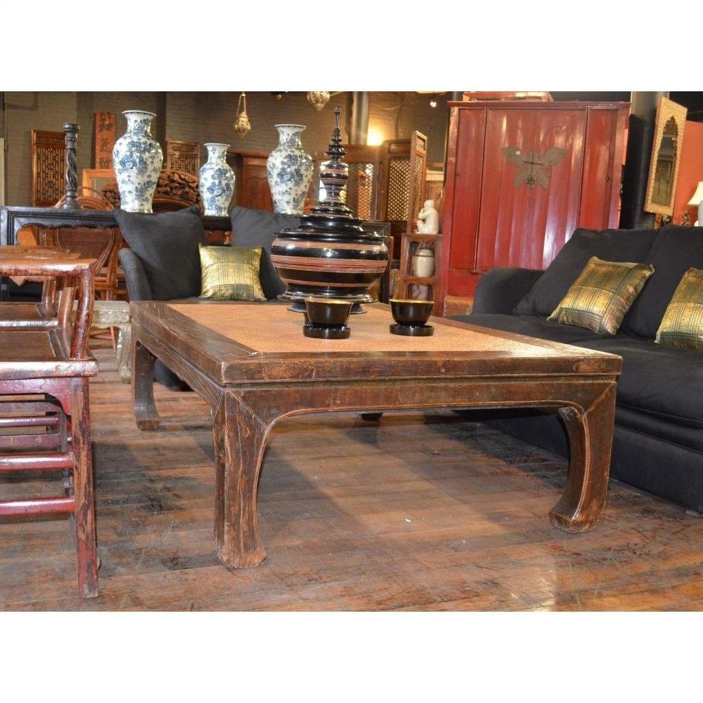 Black lacquer coffee table with elm horse hoof legs, styled in a living room with black couches and decorative vases.