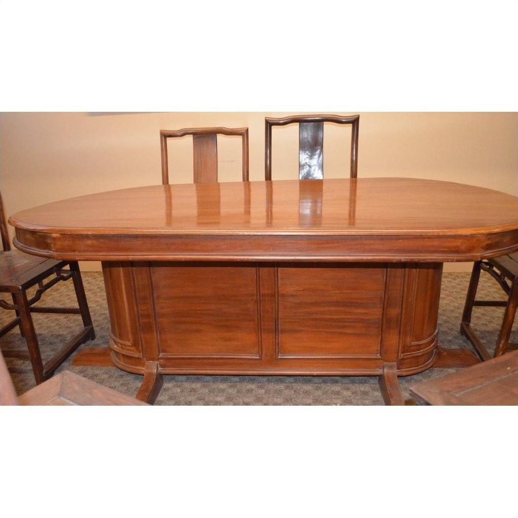 Glossy brown wooden oval pedestal dining table with four matching rustic wooden chairs, dining room setting.