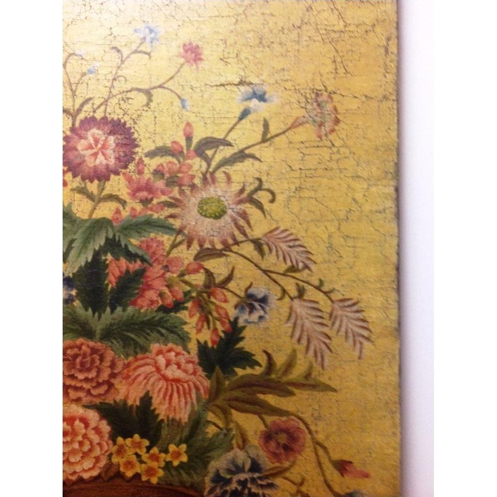 Colorful floral painting on wood with green foliage and cracked yellow background, close-up view.