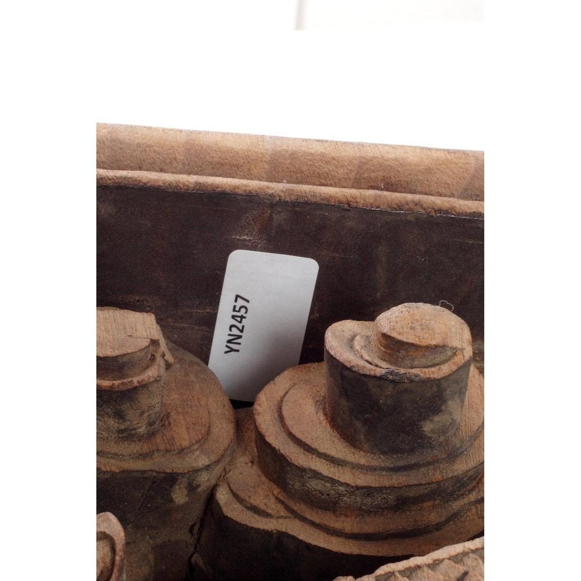 Close-up of spools next to hand-carved wooden Chinese temple corbels with characters, 18th century, on a table.