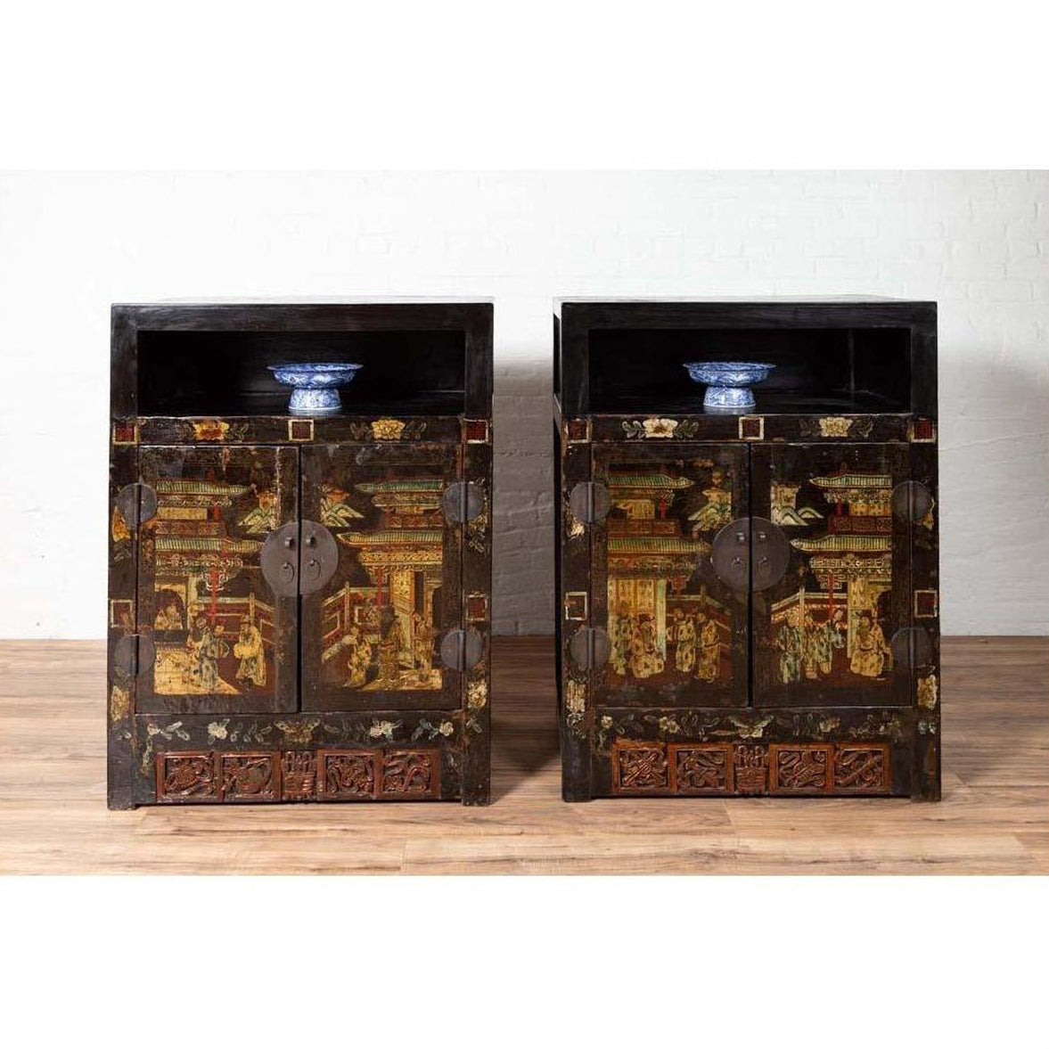 Black lacquer wood Chinese display cabinets with hand painted chinoiserie motifs, blue and white bowls on top shelves.