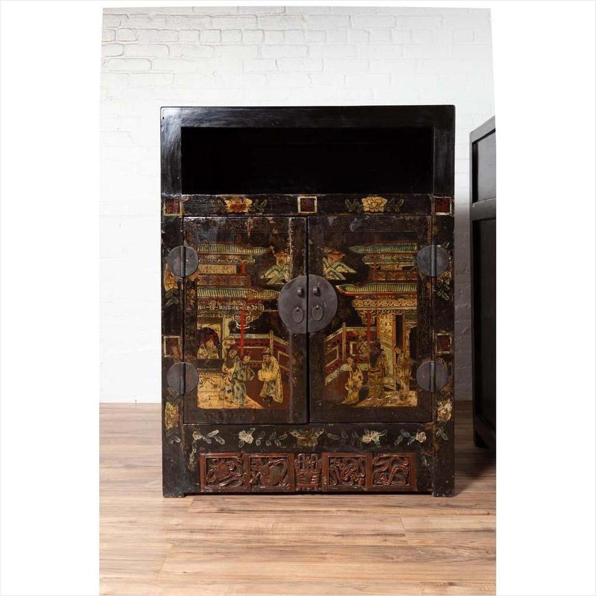 Black lacquered wooden Chinese display cabinets with hand painted chinoiserie motifs, set against a white brick wall.