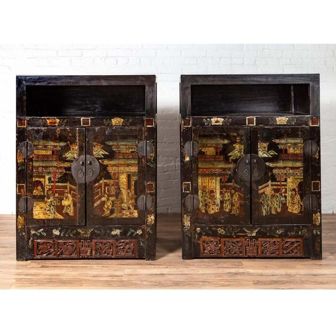 Black and gold antique Chinese wood display cabinets with hand painted chinoiserie motifs, against white brick wall.