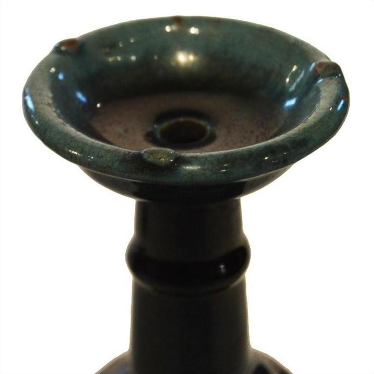 Close-up of dark green glazed ceramic antique Chinese Hunan candle holders with wide tops and narrow stems.