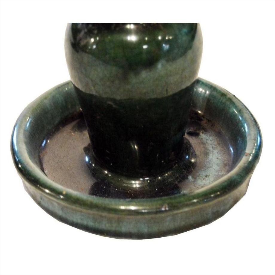 Close-up of a pair of dark green glazed ceramic antique Chinese Hunan candle holders with rounded bases.