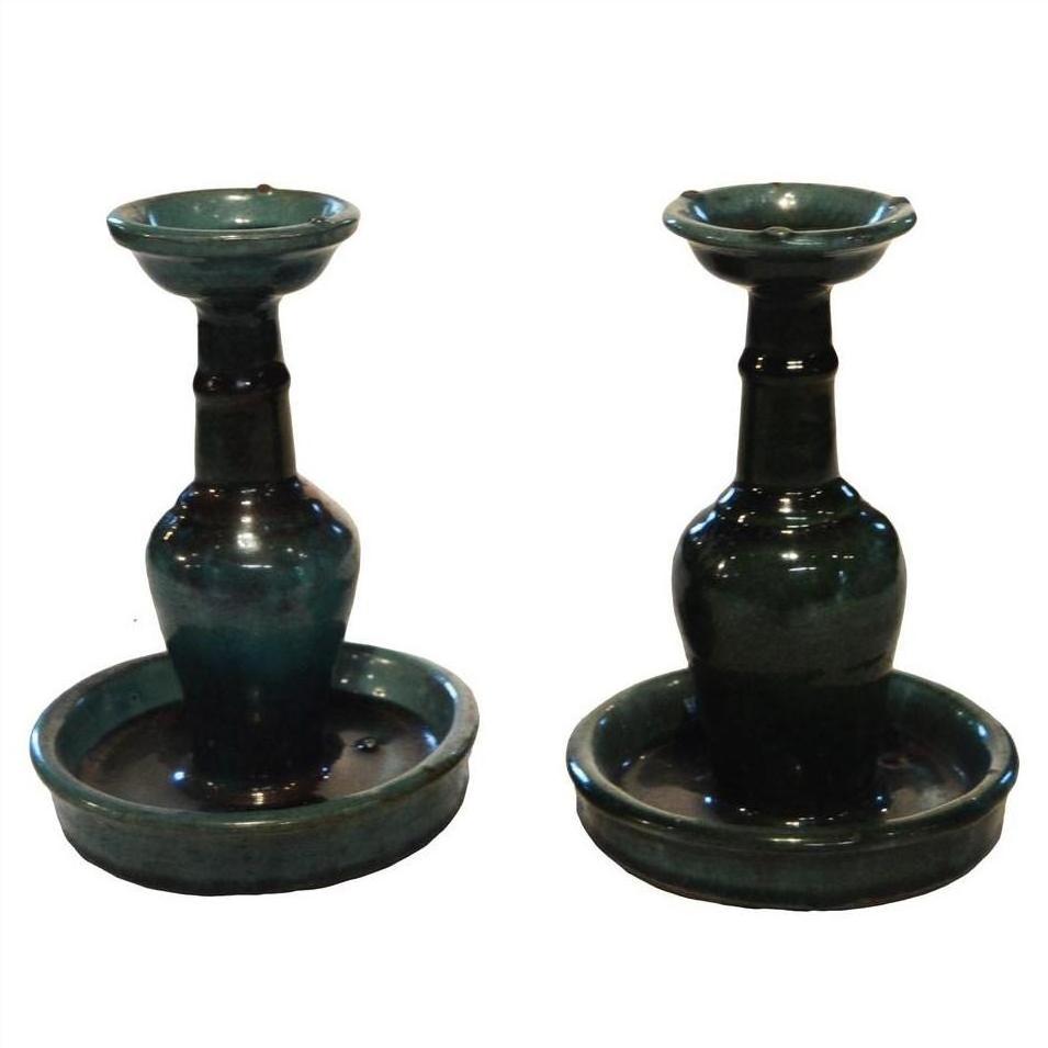 Close-up of antique Chinese Hunan candle holders with dark green glaze, wide bases, and rounded trays.