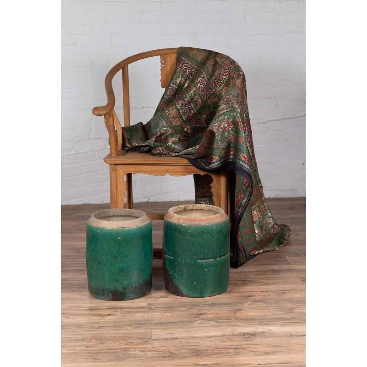 Brown wooden chair with patterned fabric seat, antique Chinese planters in front, on wooden floor, indoor setting.