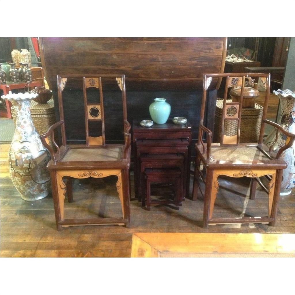 Pair of beige arm chairs with wood nesting tables, pale blue vase, and large decorative vase in living room setting.