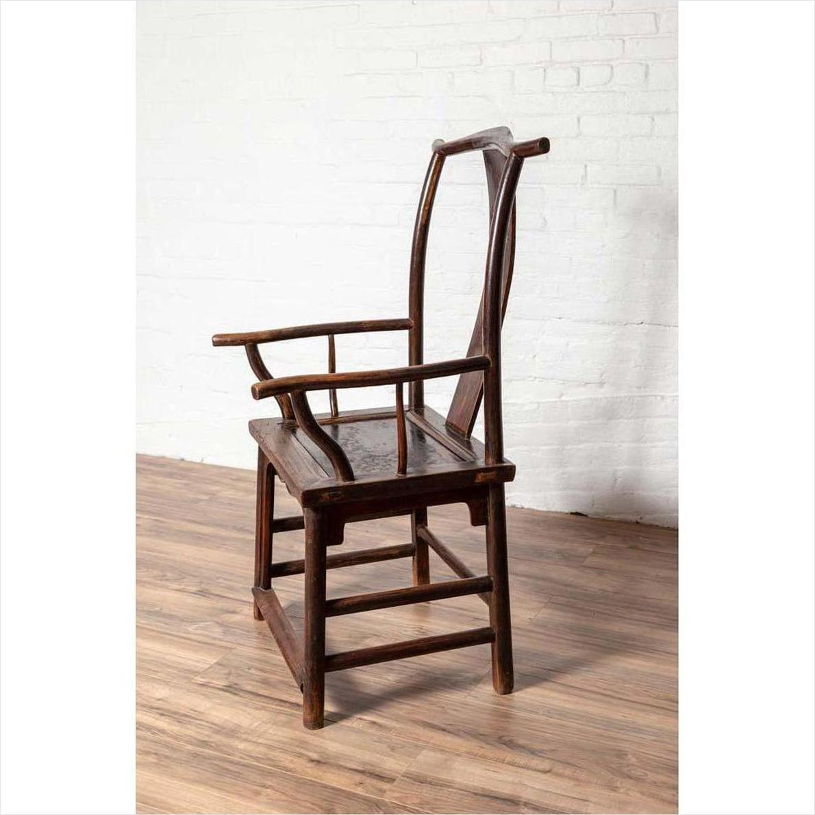 Brown wood Chinese 1880s Official's Hat Chairs with carved splats on rustic wooden floor against white brick wall.