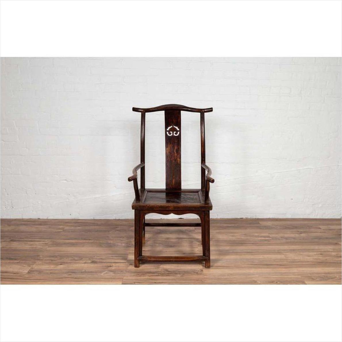 Pair of dark wood Chinese 1880s Official's Hat Chairs with carved splats on wooden floor against white brick wall.