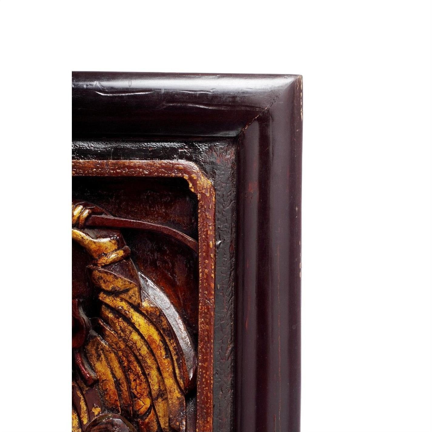 Close-up of dark wood Chinese carvings with gold-painted decorative design on the left side.