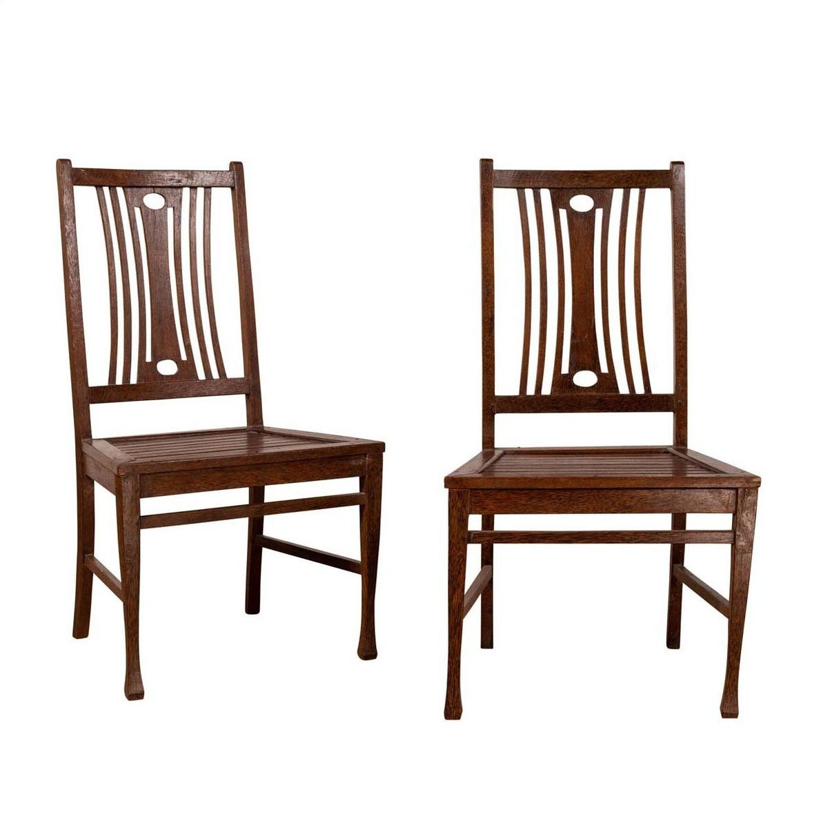 Brown wooden Indonesian side chairs with pierced splats, pair shown side by side on white background.