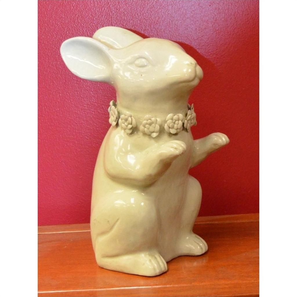 White porcelain bunny rabbit statue with a flower collar, set against a solid red background, close-up view.