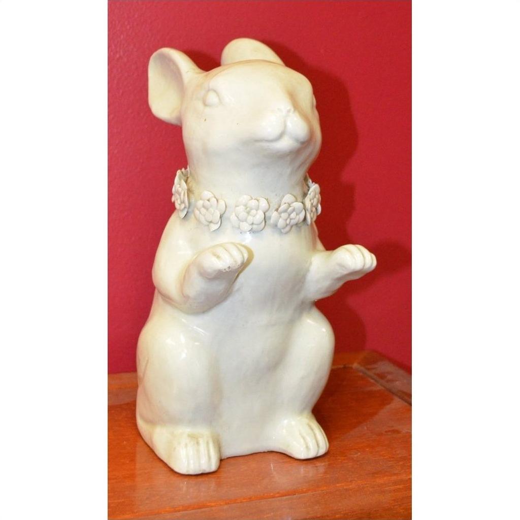 White porcelain bunny rabbit statue with floral necklace, sitting on wood, red background, close-up view.