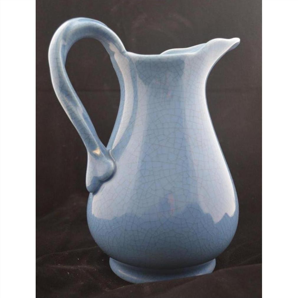 Close-up of a glossy blue crackle porcelain pitcher with curved handle against a plain dark background.