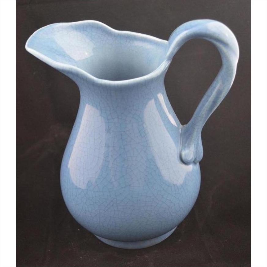Close-up of blue crackle-glazed porcelain pitcher with curved handle against a black background.