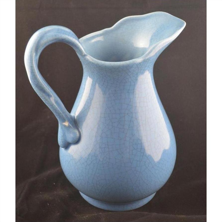 Close-up of crackle blue porcelain pitcher with curved handle and flared spout, set against a black background.