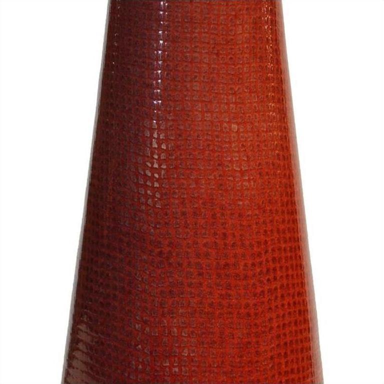 Close-up of a red ceramic vase with textured, scale-like pattern and cone shape.