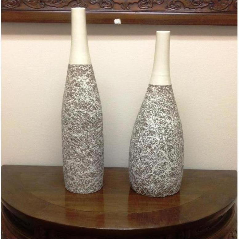 Brown and white ceramic vases, two tall assorted sizes, close-up on a wooden table.