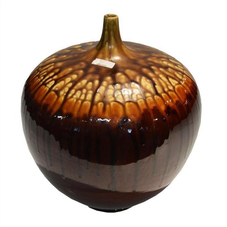 Glossy brown and tan ceramic jar with acorn-like design, round shape, on white background, close-up.