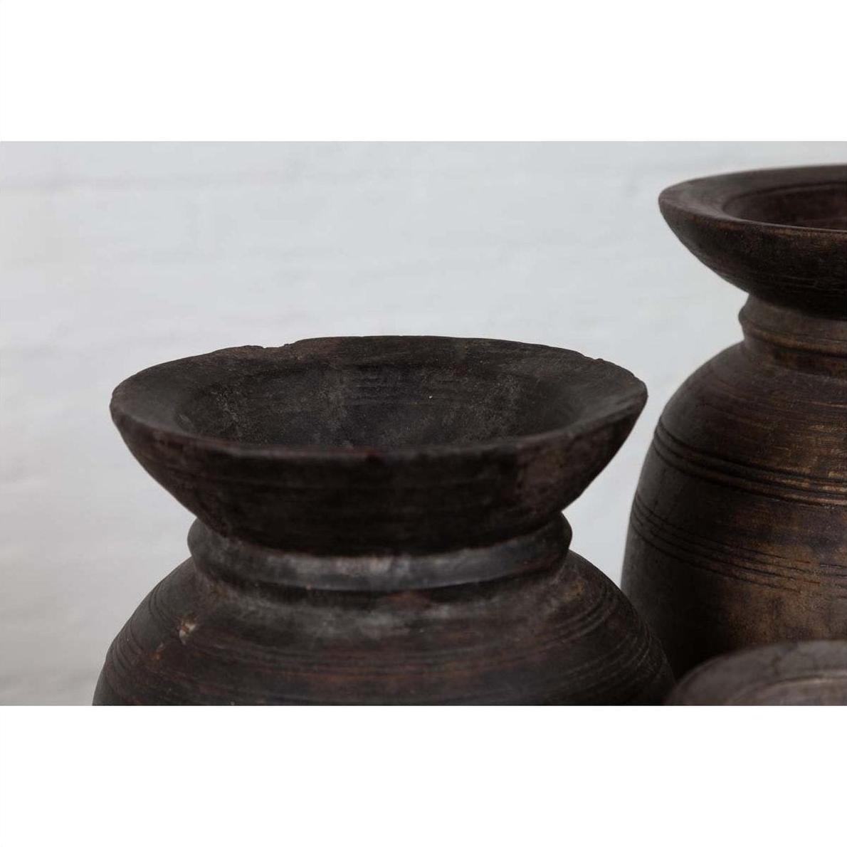 Close-up of brown wooden ghee pots with rustic finish, grouped together, primitive Nepalese style.