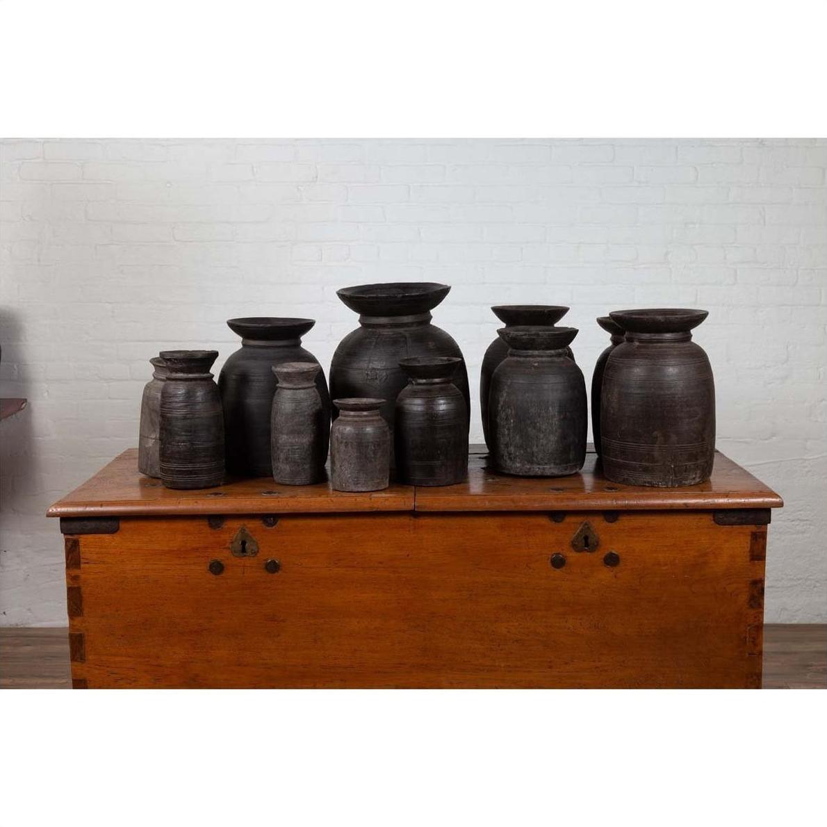 Brown wooden ghee pots on a chest against a white brick wall indoors.