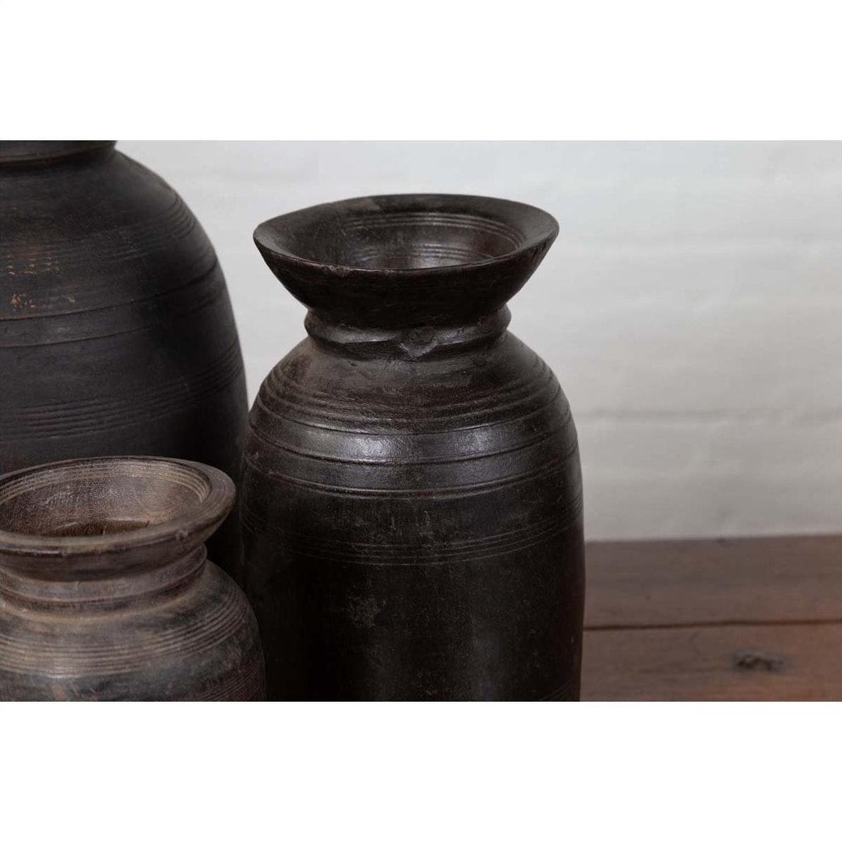 Brown wooden ghee pots in a set of three on a wooden surface with a light background.